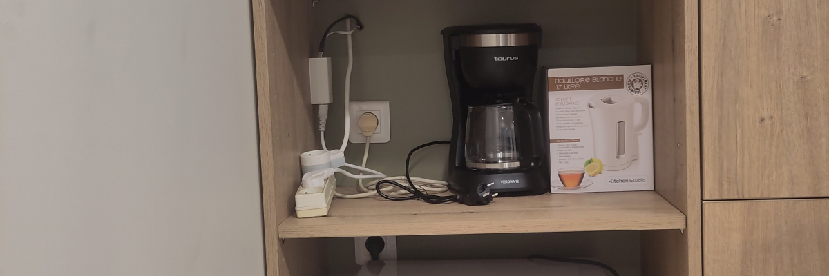 Étagères avec micro-ondes, cafetière, bouilloire, et un évier.