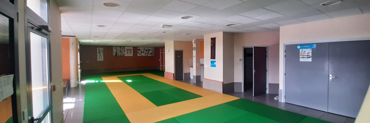 Hall avec sol vert et jaune, portes, tableaux d'affichage et éclairage au plafond.