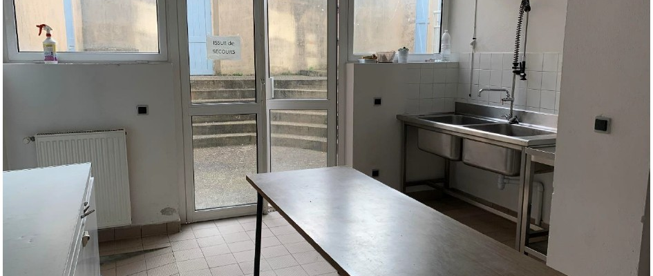 Salle avec table, évier, portes, fenêtres et radiateur.