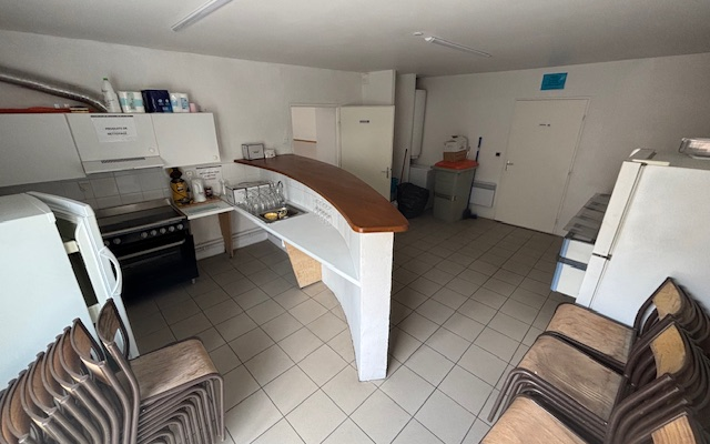 Cuisine avec comptoir, placo, frigo, évier, table et chaises.