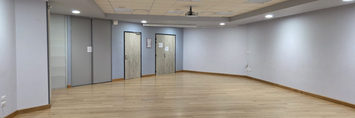 Salle vide avec éclairage encastré, portes et plancher en bois.