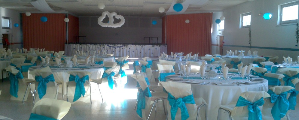 Salle avec tables, chaises, nappes, serviettes et décorations.