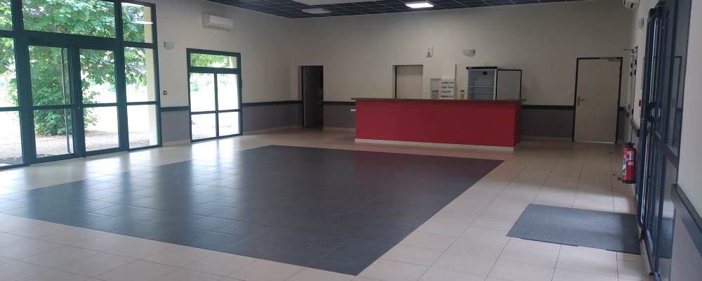 Salle avec sol en carrelage, comptoir rouge, portes, fenêtres et extincteur.