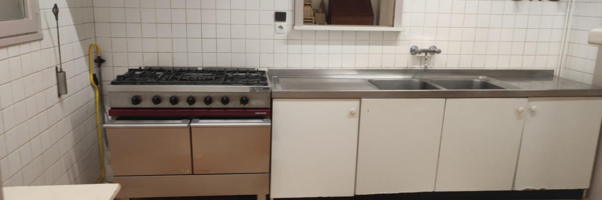 Cuisine avec cuisinière, évier, placards et hotte.