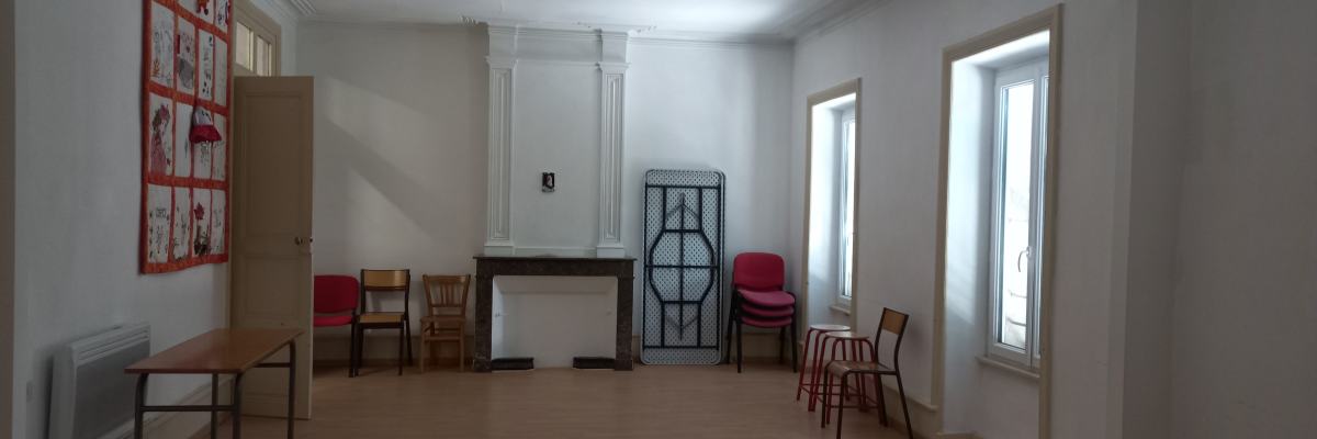 Salle avec chaises, tables, radiateur, tableau d'affichage et cheminée.