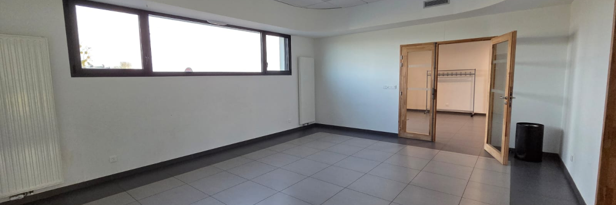 Pièce vide avec carrelage, radiateur, fenêtres, porte et placard.