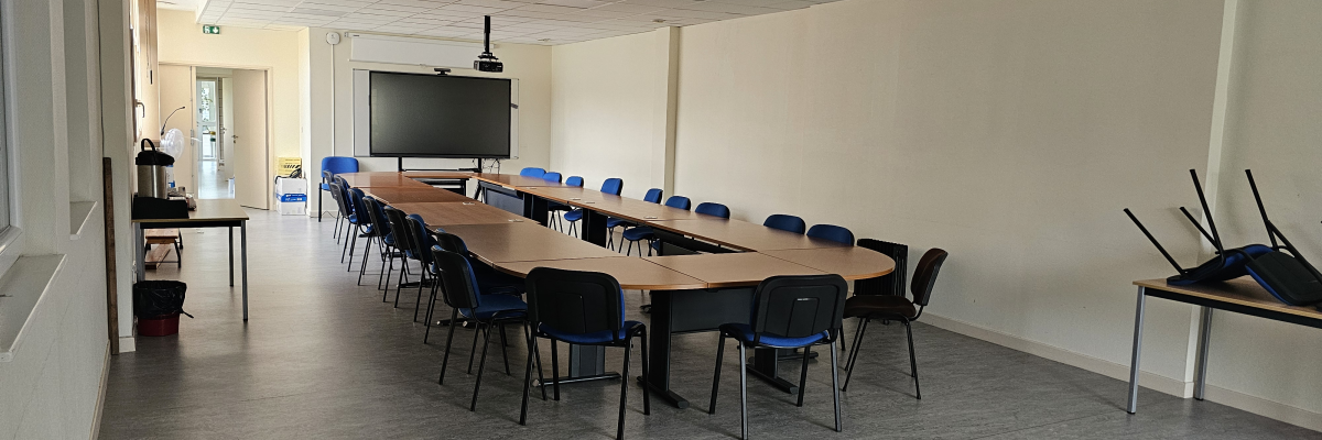 Salle avec tables, chaises, écran, caméra.