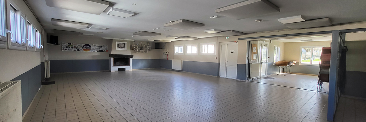 Salle vide avec sol carrelé, fenêtres, lumières et porte.