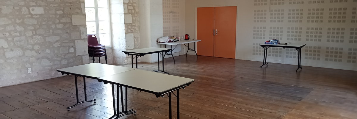 Salle avec tables, chaises, portes orange et murs en pierre.