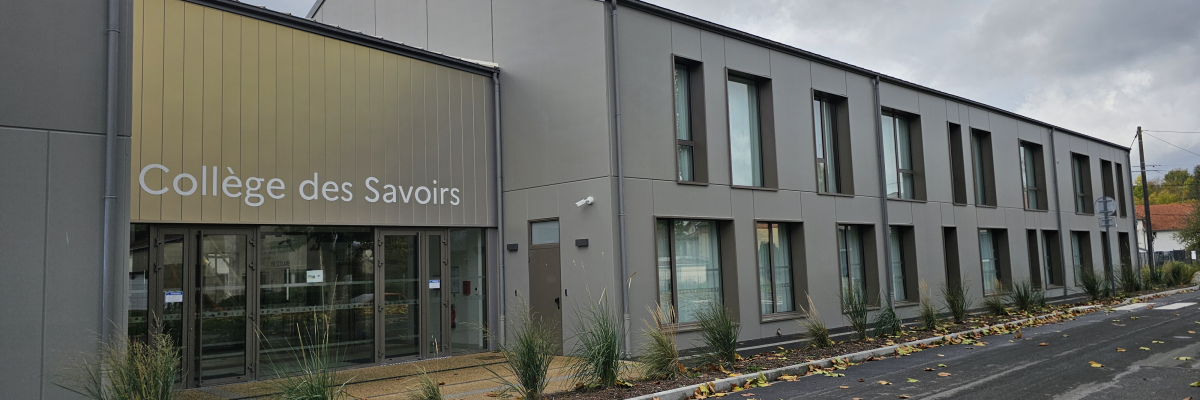 "Bâtiment gris moderne avec façade vitrée, portant l'enseigne 'Collège des Savoirs', bordé de plantes."