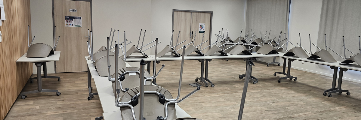 Salle de classe avec tables, chaises et écrans.