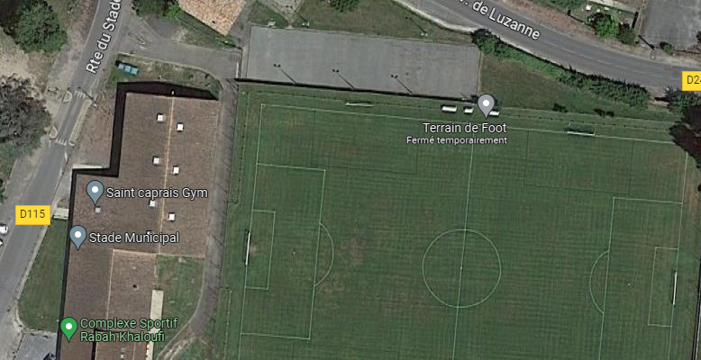 Vue aérienne d'un terrain de football et d'un stade avec des bâtiments adjacents et des routes.
