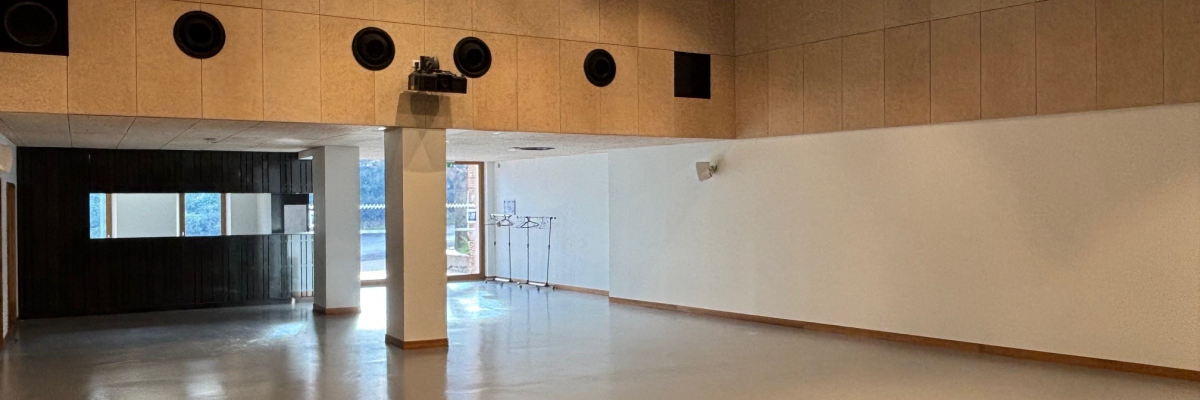 Salle vide avec éclairage, haut-parleurs, et porte vitrée.