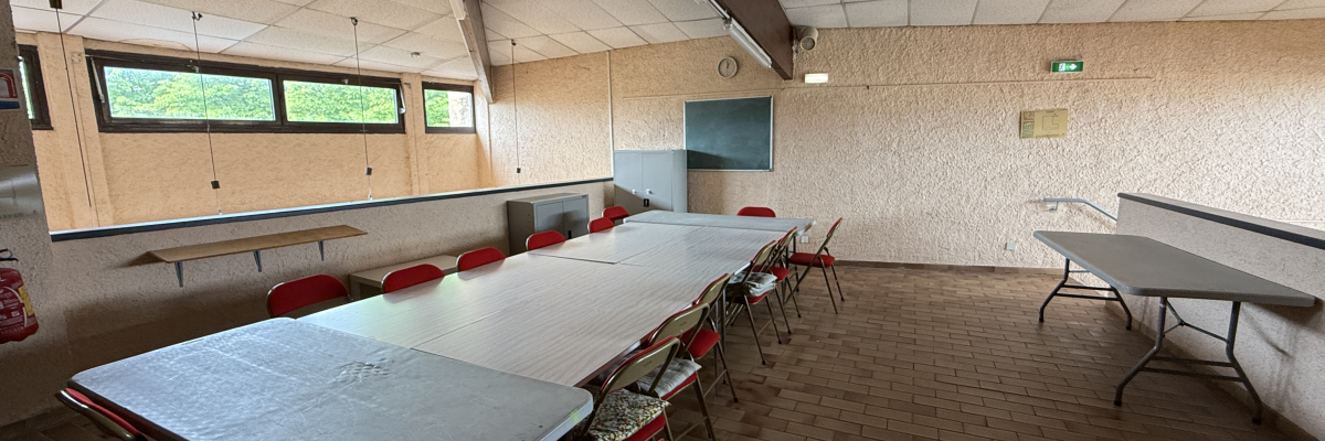 Salle avec tables, chaises, lavabo, miroir, extincteur, tablettes et poubelles.