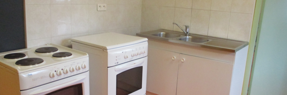 "Cuisine avec four, plaque de cuisson, évier, robinet et armoire."