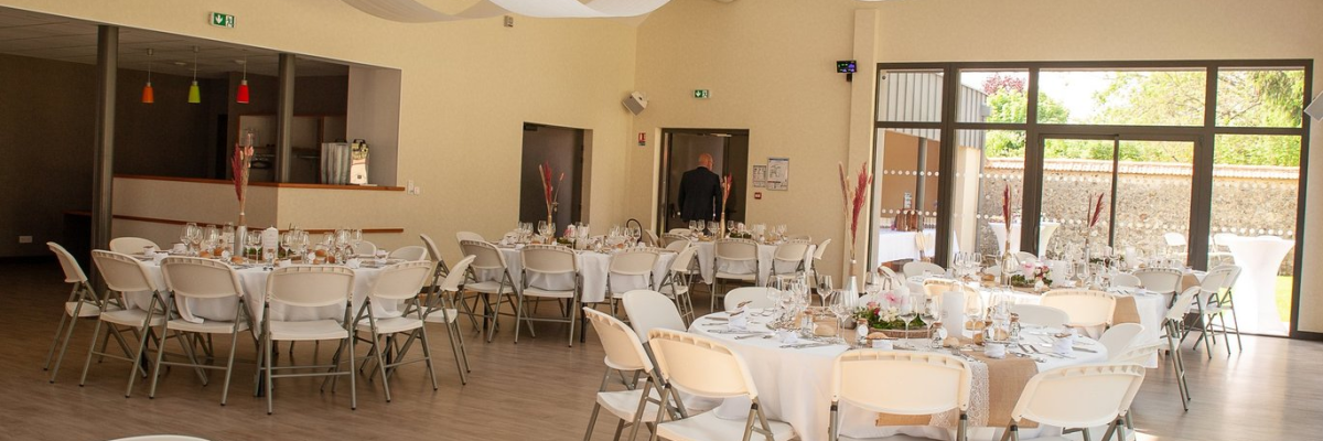 Salle avec tables rondes, chaises, décorations et nourriture.