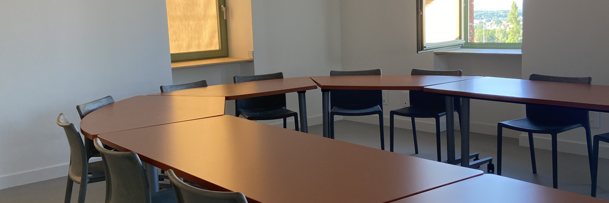 Salle avec tables, chaises et fenêtres.