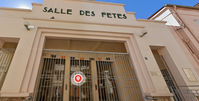 "Entrée de salle des fêtes avec grilles, portes vitrées, enseigne et lampes."
