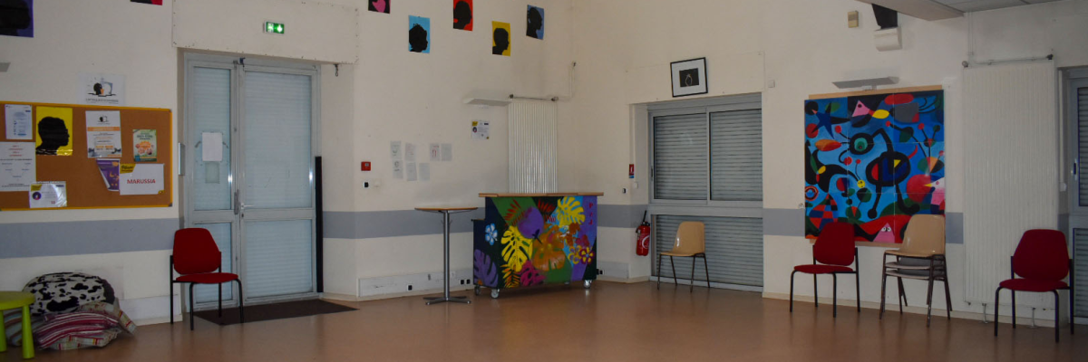 Salle avec chaises, tableaux, porte, fenêtre et matériel de jeu.