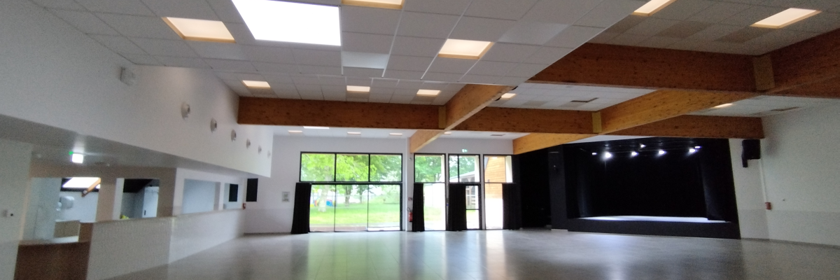 Salle vide avec plafond à plaques, lumières encastrées, grandes fenêtres et porte en verre.
