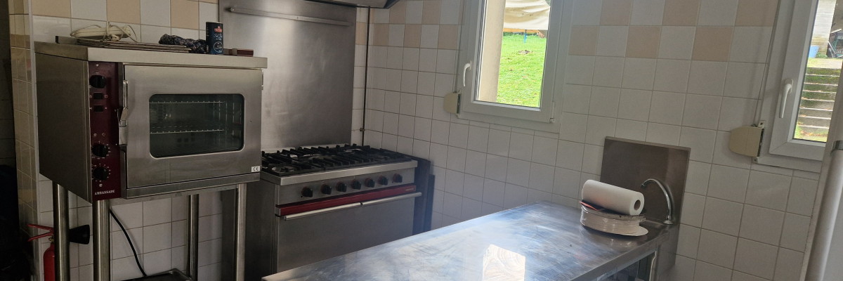 Cuisine avec four, plaque de cuisson, hotte, table inox, essuie-tout, et tiroirs inox.