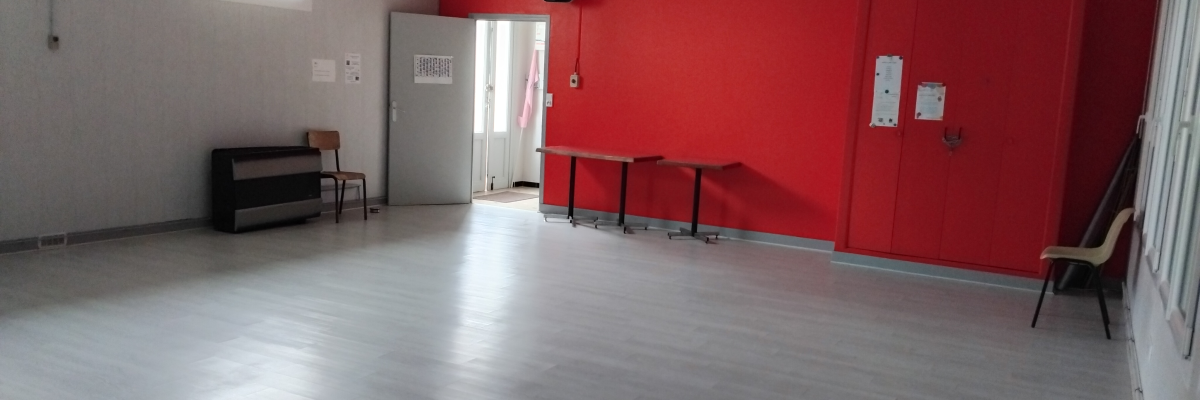 Salle avec mur rouge, table haute, tabourets, armoire, chaise, porte.