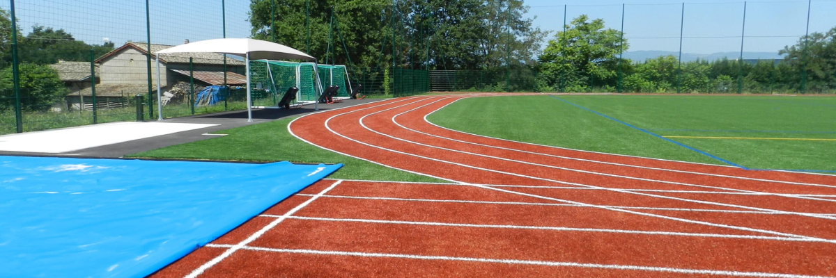 Stades d'athlétisme avec quatre pistes, gazon, un long saut de gare, et des installations de saut en hauteur.