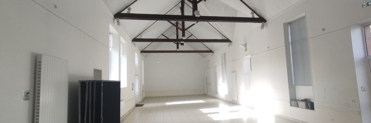 Salle vide avec radiateur, projecteur et structure de plafond.