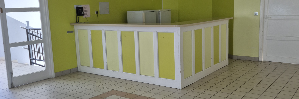 Comptoir de réception, sol carrelé et porte.