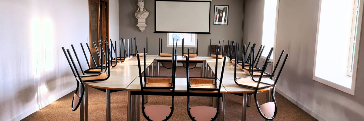 Salle avec table, chaises, écran, vidéo projecteur et buste.
