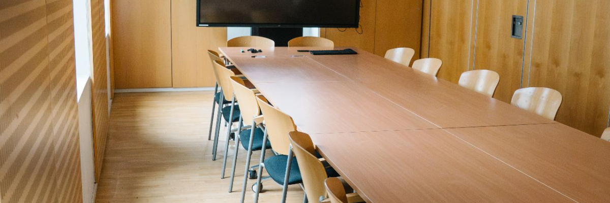 "Salle avec table, chaises, écran et porte."