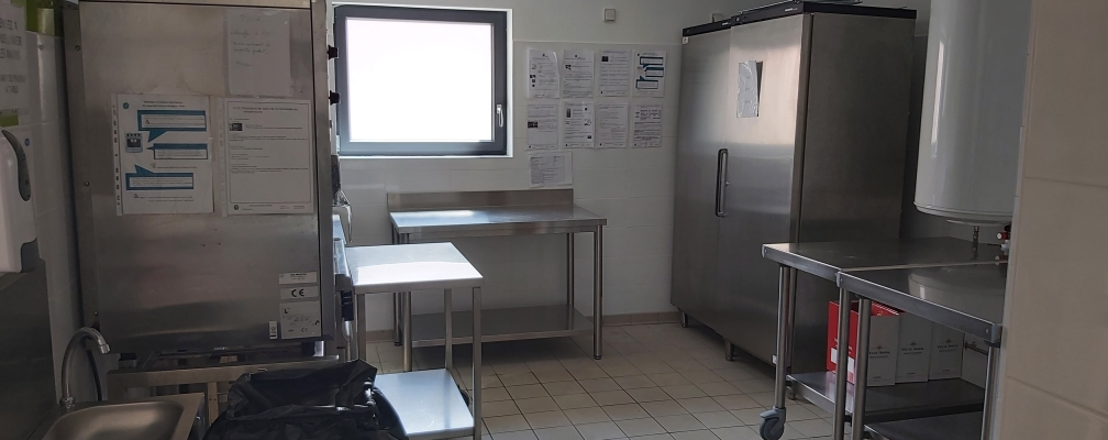 Laboratoire avec tables, chariots, évier, hotte, armoire et affiches.