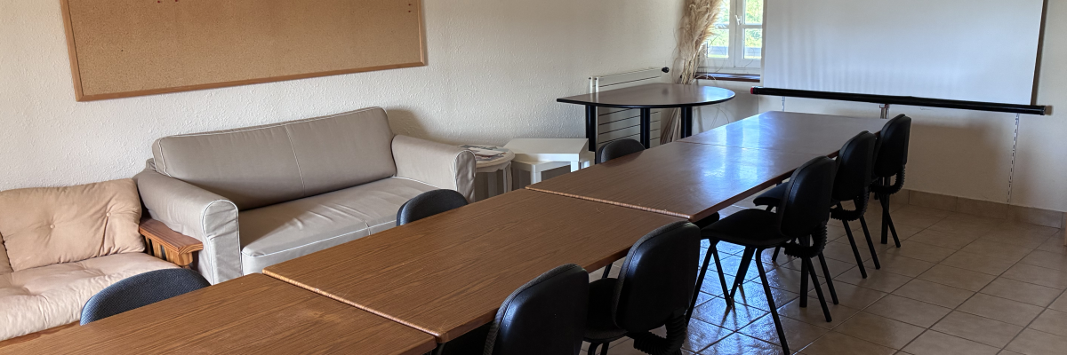 Salle avec table, chaises, canapé, tableau d'affichage et écran.