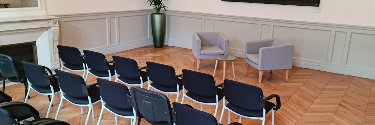 Salle avec chaises, table, tableau et lustre.