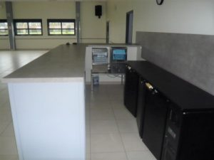 Cuisine avec plans de travail, four, plaques de cuisson, hottes, et évier.