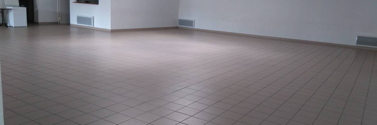 Salle vide avec écran, sol carrelé, lumières et climatiseurs.