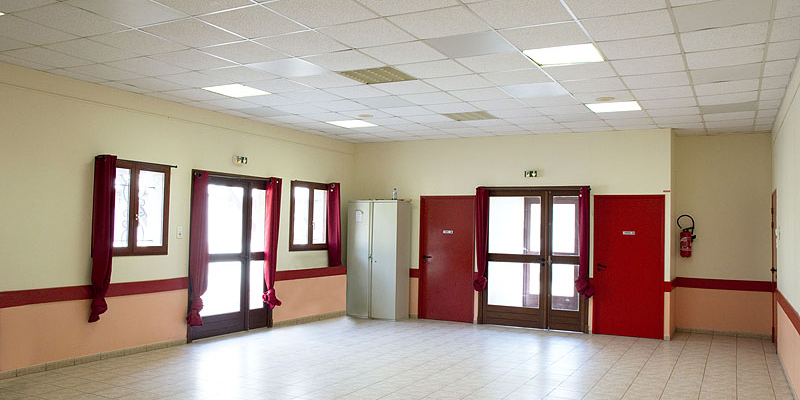 Salle vide avec portes, fenêtres, extincteur et placard.