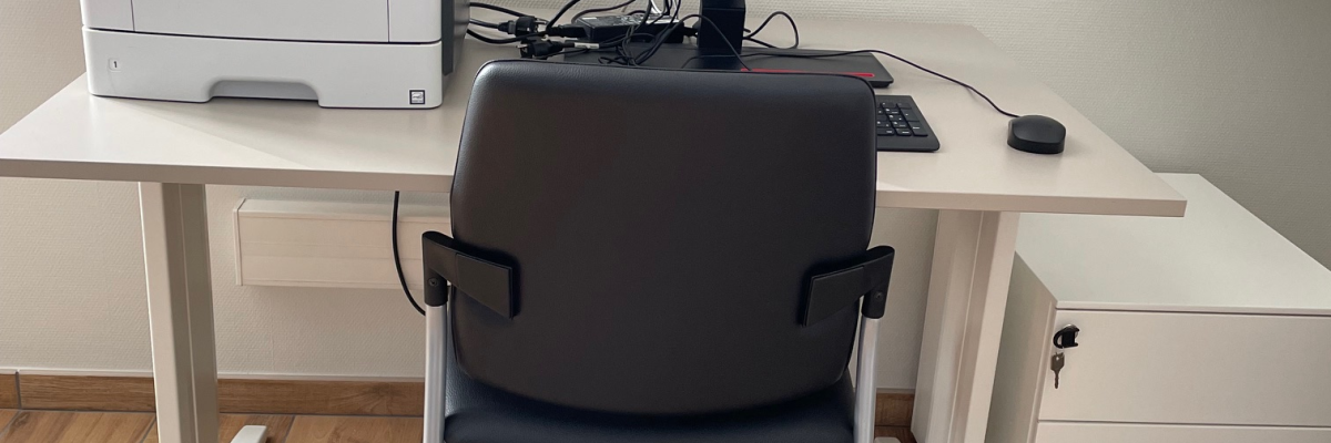 Bureau avec imprimante, écran d'ordinateur, souris, clavier, chaise et tiroirs de rangement.