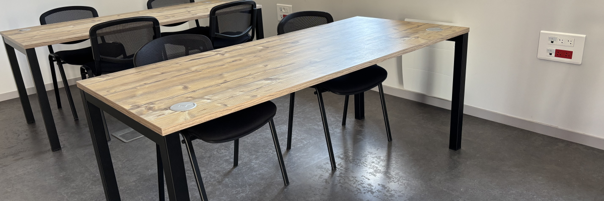 Salle avec table, chaises, prise électrique et fenêtre.