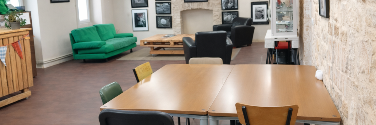 Salle avec table, chaises, canapé, vitrines et photos murales.