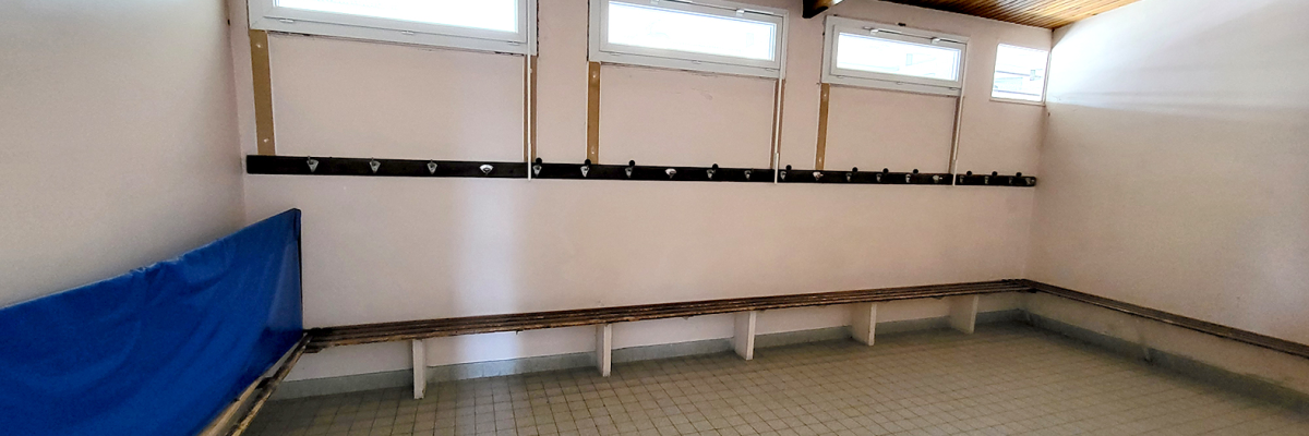 Salle avec bancs, fenêtres et sol carrelé.