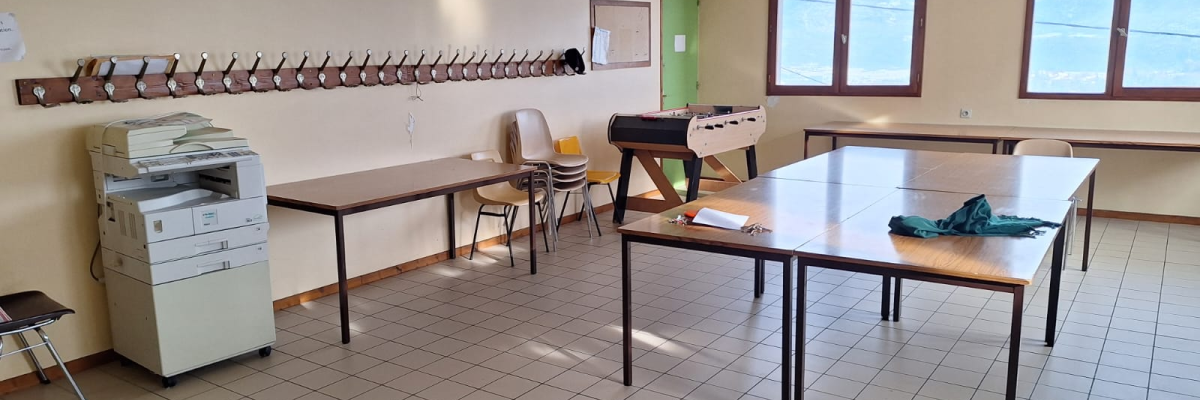 Salle avec imprimante, tables, chaises, rideaux et casiers.