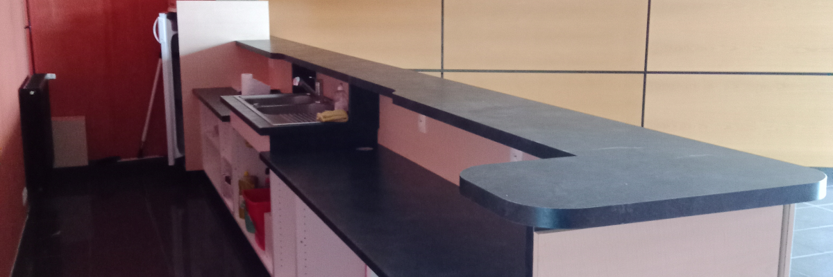 Comptoir, tiroirs, étagères, corbeille à papier, porte, poubelle, plinthe, prise électrique.