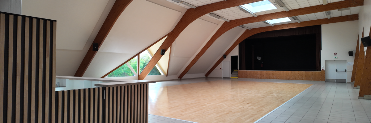 Salle avec plancher en bois, murs en brique, fenêtres, comptoir et porte.