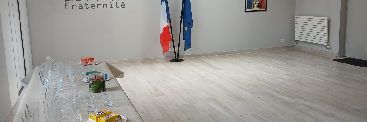 Salle avec table, verres, nourriture, drapeaux, radiateur et affiches murales.