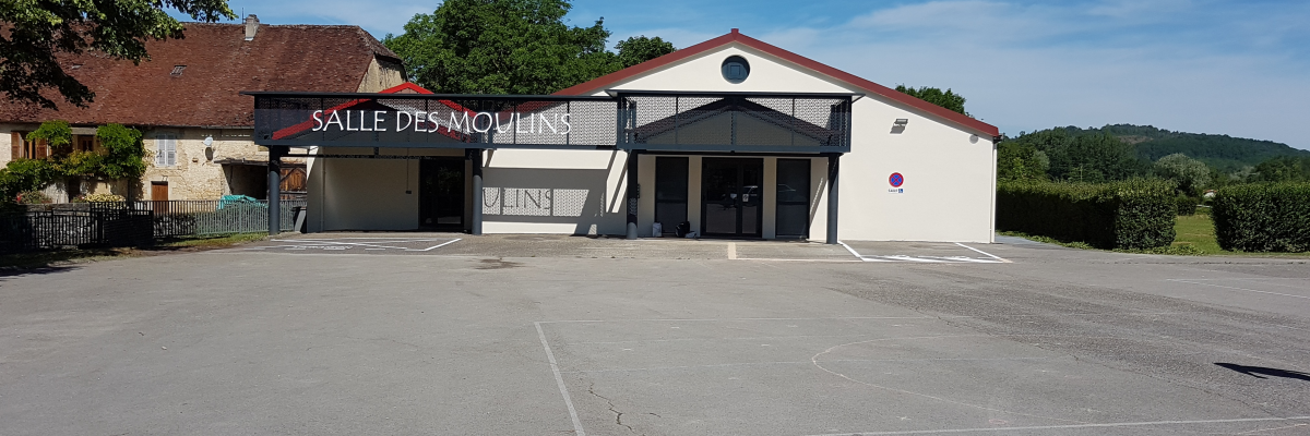 Bâtiment avec parking et panneau "Salle des Moulins".