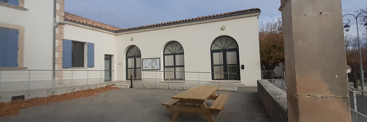 Bâtiment avec entrée, fenêtre et banc de pique-nique extérieur.