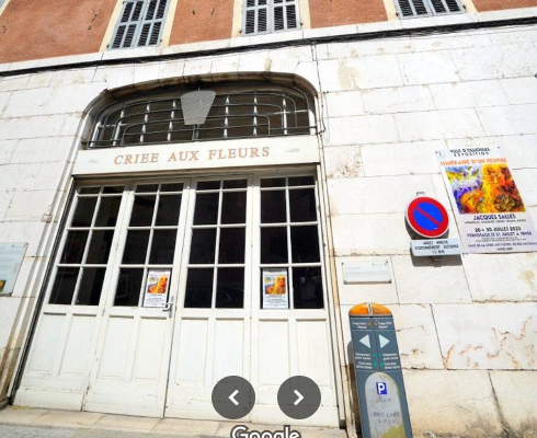 "Grandes portes vitrées, enseigne "CRIEE AUX FLEURS", panneaux d'affichage, parcmètre."