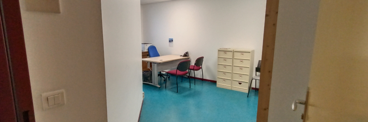 Bureau avec table, chaises, armoire et ordinateur.