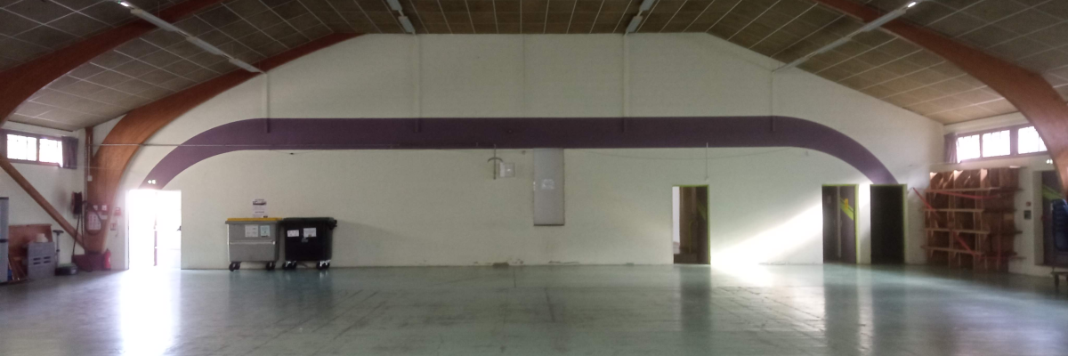 Salle spacieuse avec sol lisse, piliers, éventail, portes et étagères.